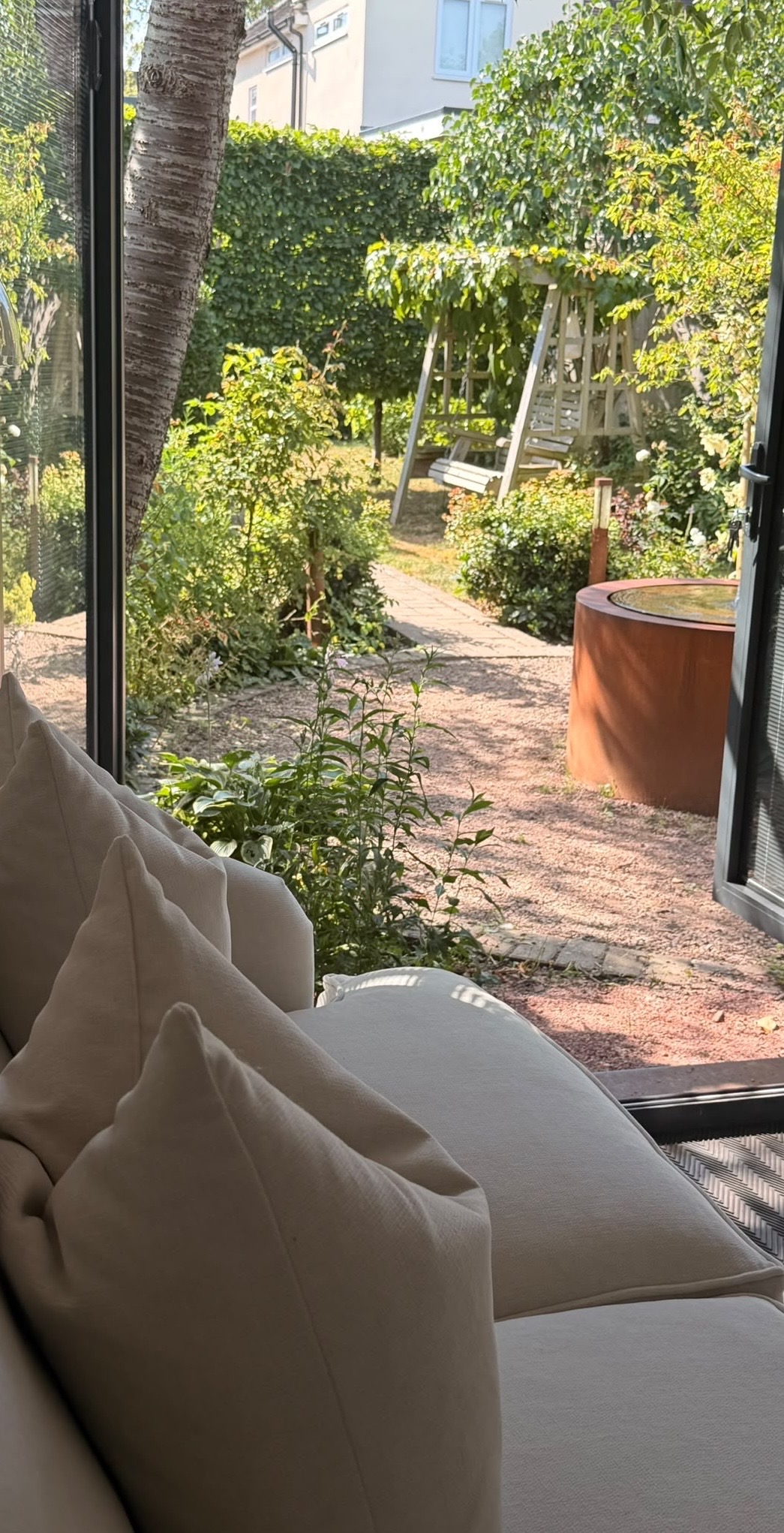 View from the studio sofa with cream cushions out over the gravel path and planting