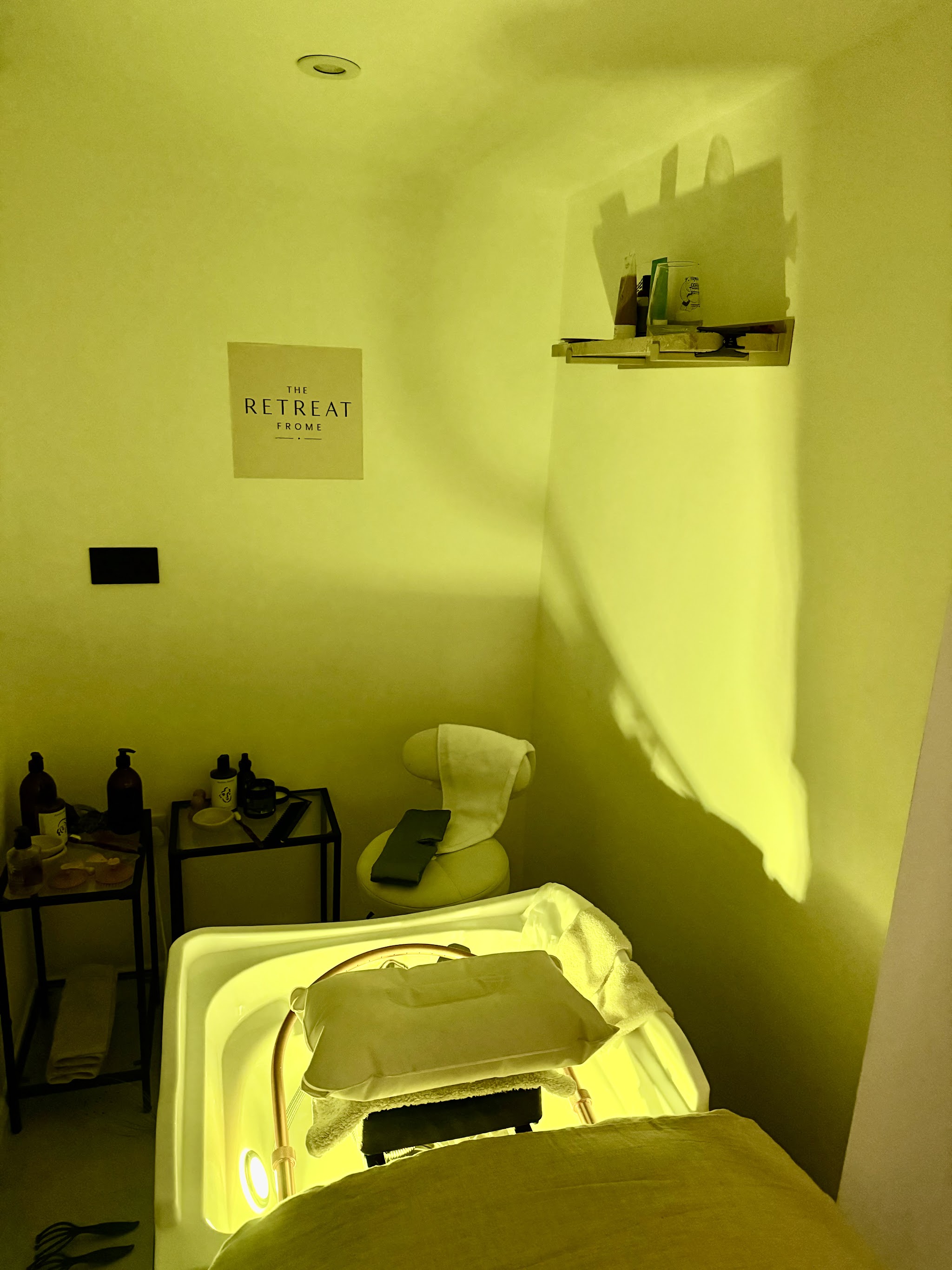 The treatment room in soft coloured light, with the head spa bed and basin and The Retreat print on the wall