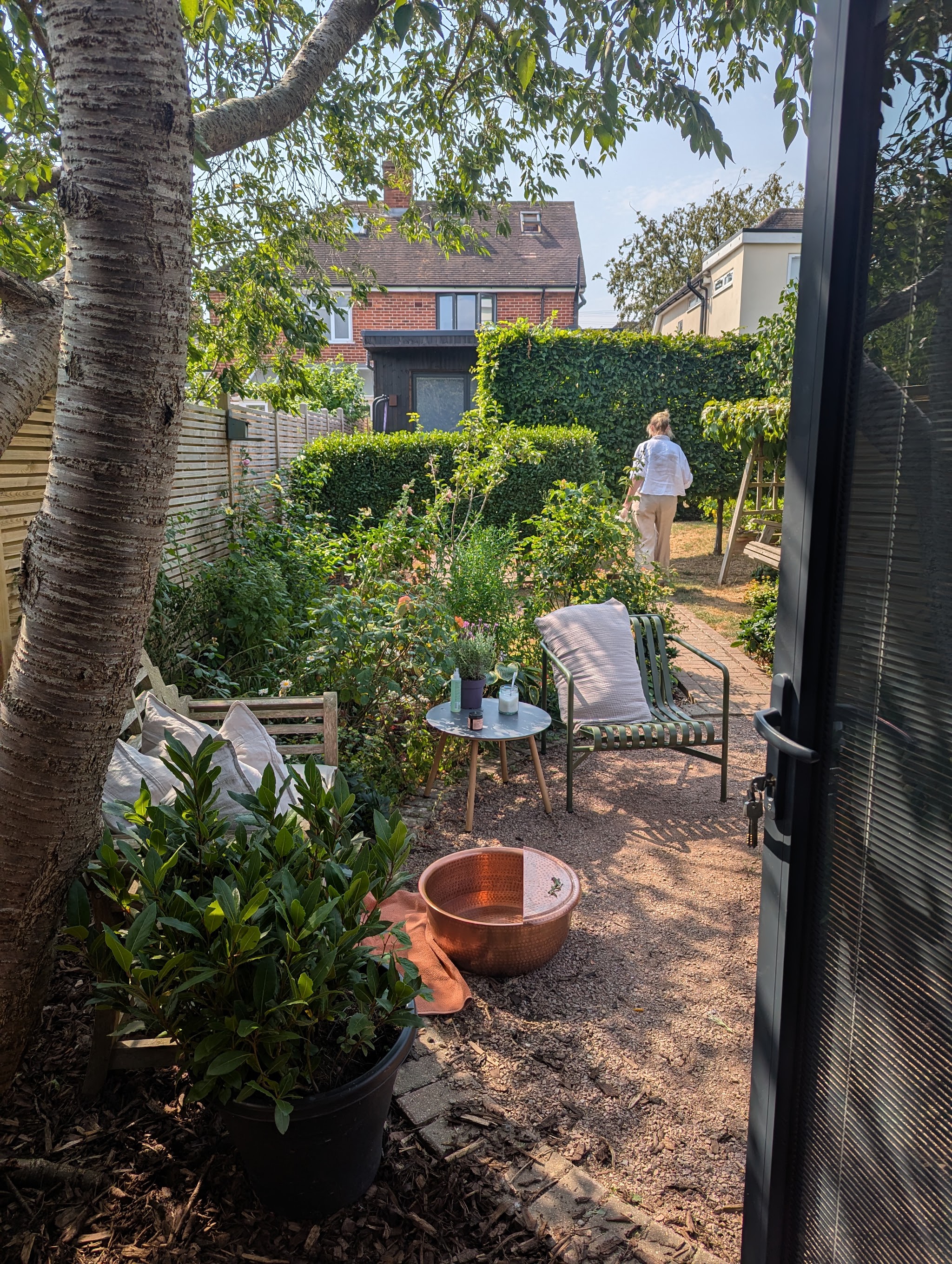 Looking out from the studio doors over the garden, with seating and a copper bowl among the planting
