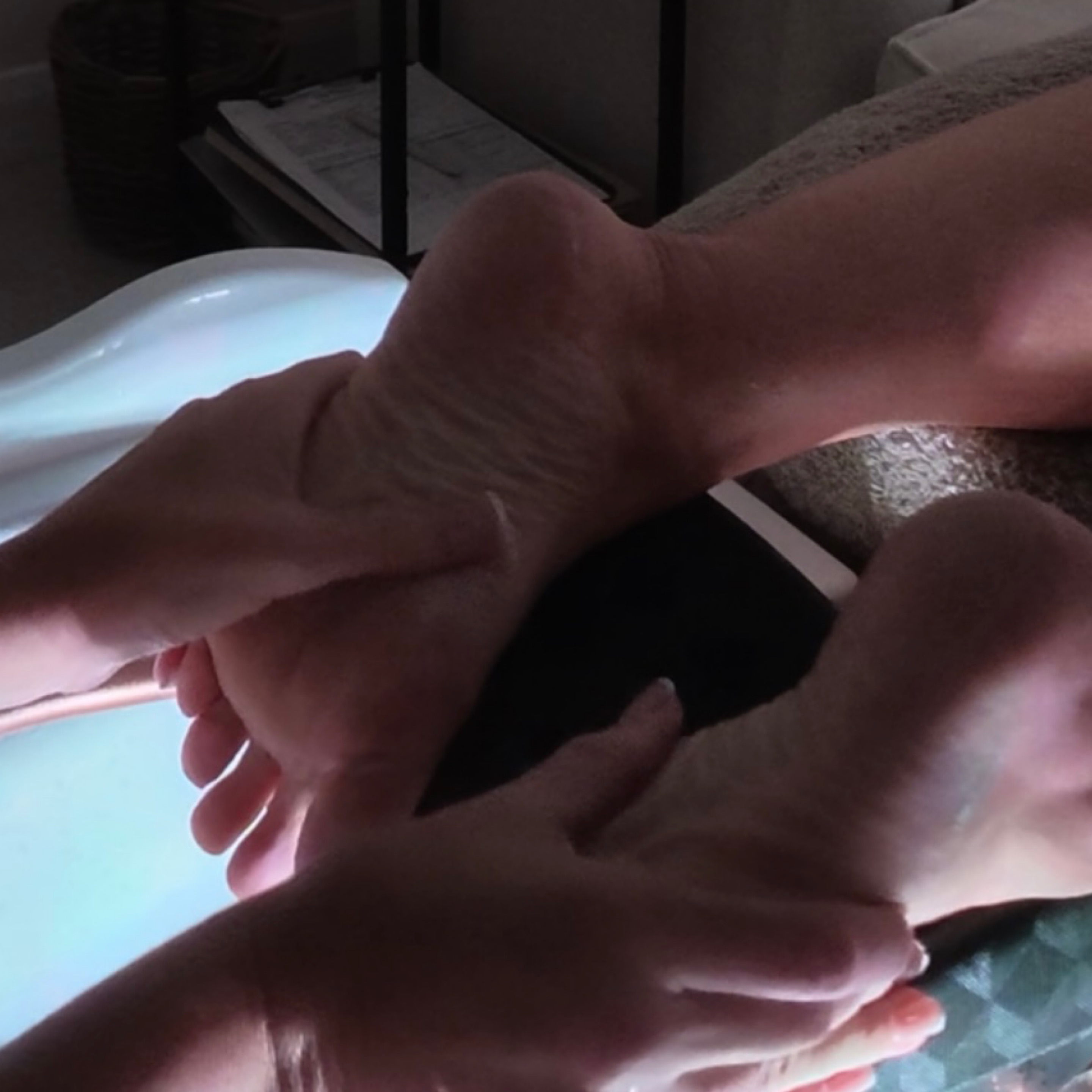 Hands massaging a client's foot over the softly lit foot spa basin
