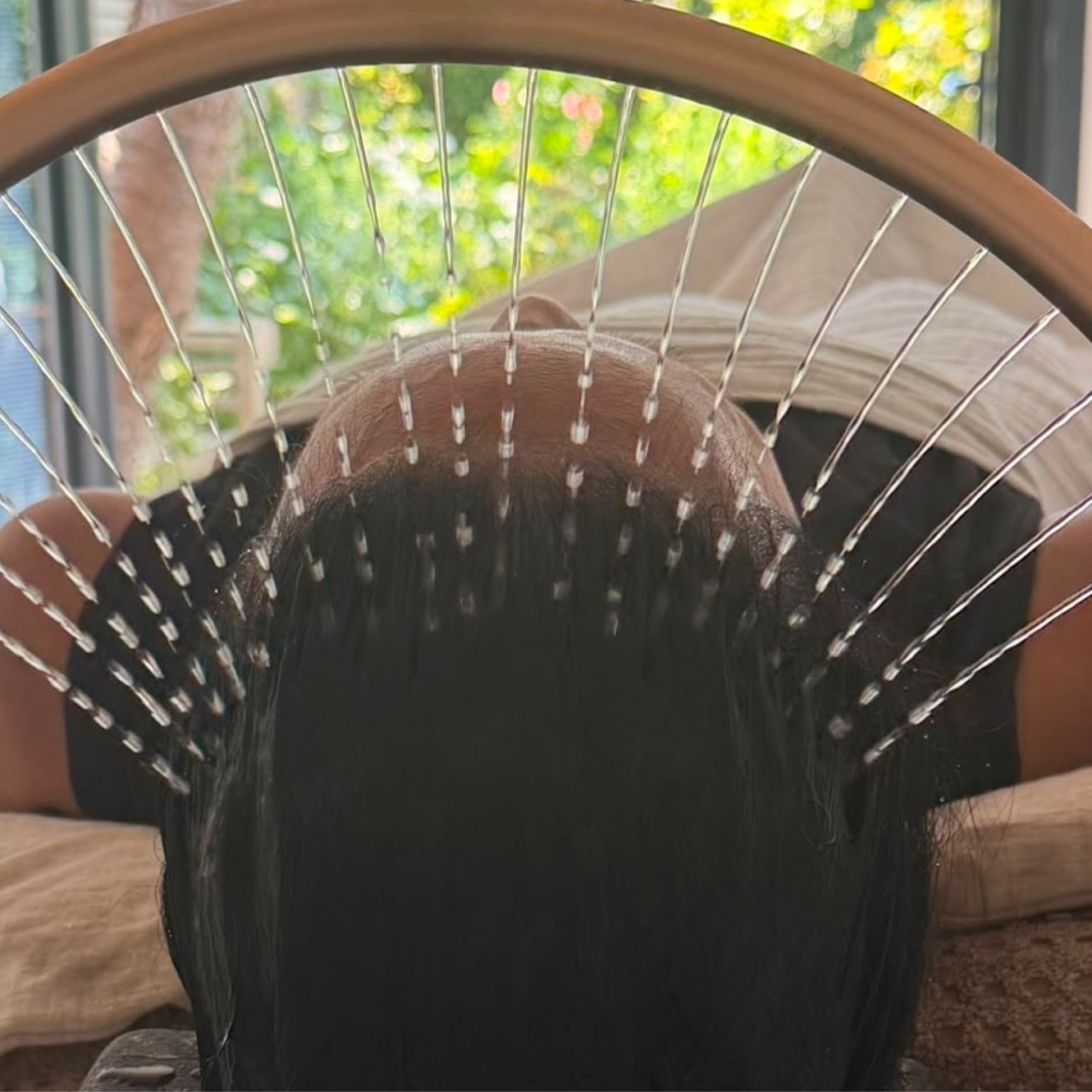 The head spa in progress: warm water flowing through the halo ring over a client's hair, with the garden beyond the glass